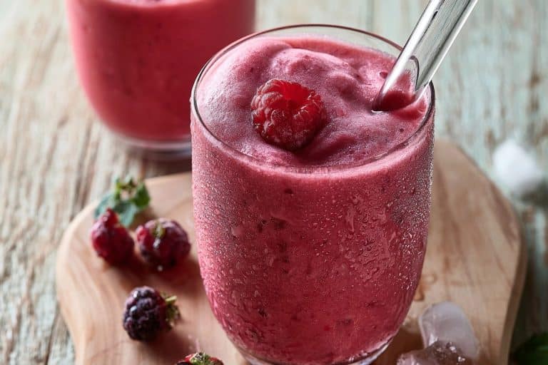 Un smoothie onctueux aux fruits rouges dans un verre givré sur une table avec des baies fraîches