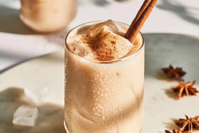 Un frappé glacé onctueux dans un verre avec de la cannelle et des épices sur une table marbrée